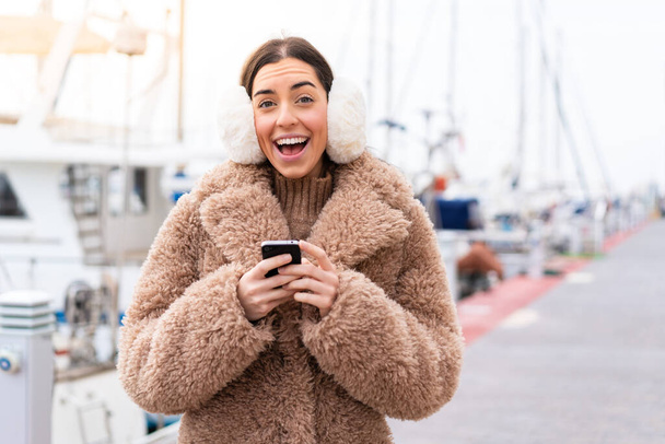 Fiatal nő visel téli mandzsettát a szabadban meglepett, és üzenetet küld - Fotó, kép