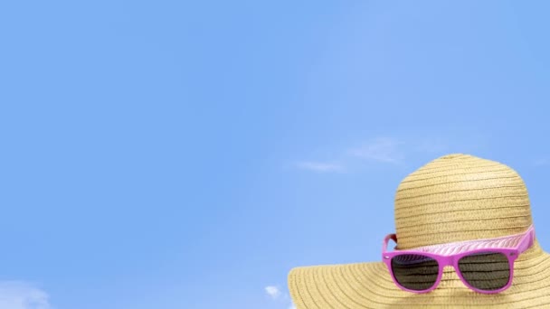 Güneşli bir günde mavi gökyüzünde yaz güneşi hasır şapkası. Güneş gözlüğü yaz konsepti fotokopi alanı mavi arka plan rahatlama, tatil, seyahat, plaj, güneş konsepti yakın çekim - Video, Çekim
