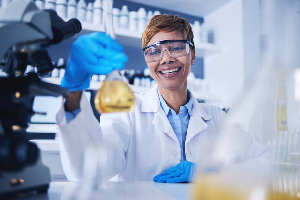 Tudomány, folyékony és fekete nő a laboratóriumban mosollyal a kutatás, orvosi vizsgálat és kísérlet. Egészségügyi, gyógyszerészeti és női tudós üveg főzőpohárral minta, gyógyszer és vakcina. - Fotó, kép