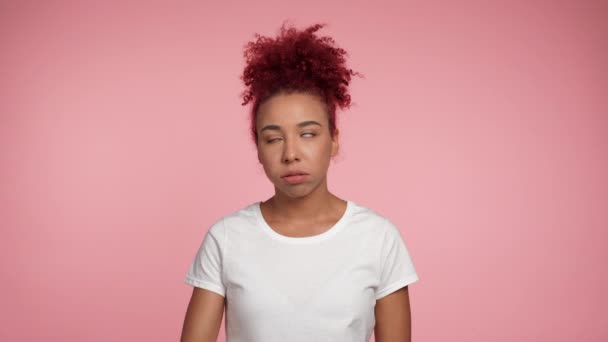 Portrét zklamaný Afroameričan ryšavý kudrnatý žena tvář dlaň třesoucí hlavu dotýkající tvář v zoufalství vypadající fotoaparát. Žena v bílém tričku stojící na izolovaném růžovém pozadí s kopírovacím prostorem - Záběry, video