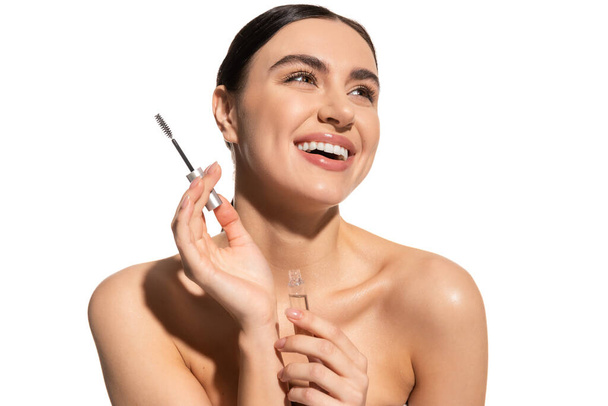 happy brunette woman holding eyebrow brush and styling gel isolated on white  - Foto, Imagem
