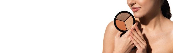vue recadrée de la jeune femme avec épaule nue tenant bronzant et surligneur palette isolé sur blanc, bannière  - Photo, image