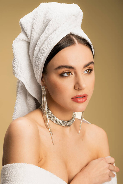 young woman in luxurious jewelry posing with towel on head on beige  - Foto, Bild