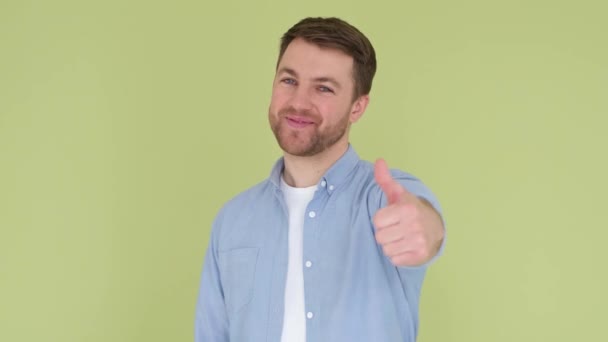 Portrait of guy showing thumbs up on studio background. He laughs and his eyes light up with joy. - Materiaali, video