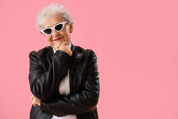 Thoughtful senior woman in sunglasses on pink background - Foto, imagen