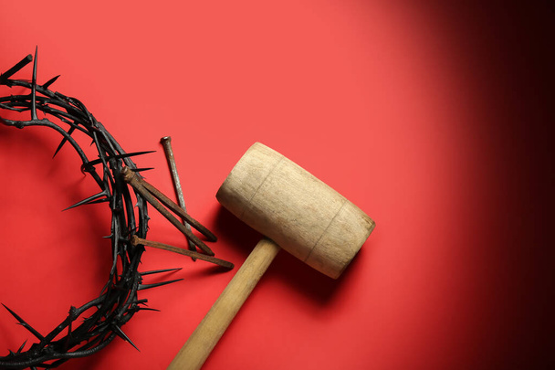 Crown of thorns with nails and mallet on red background - Photo, Image