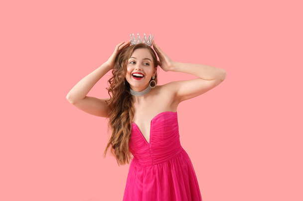 Young woman in crown and bright prom dress on pink background - Fotografie, Obrázek