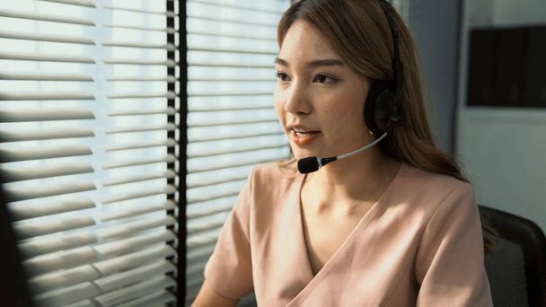 Competent female operator working on computer and while talking with clients. Concept relevant to both call centers and customer service offices. - Photo, image