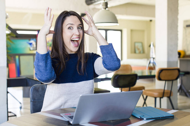 young pretty woman screaming with hands up in the air. telecommuting concept - 写真・画像