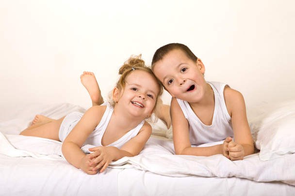 Niños divirtiéndose holgazaneando en la cama
 - Foto, Imagen