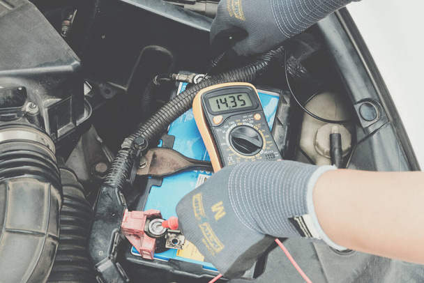 テストメーター車のメンテナンスと車のバッテリーの機械的な手のチェック電圧 - 写真・画像