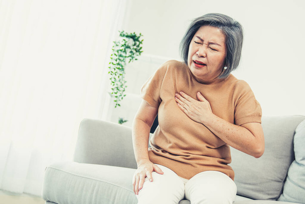 Агонизирующая пожилая женщина испытывает боль в груди. Медицинская помощь, уход за пожилыми людьми. - Фото, изображение