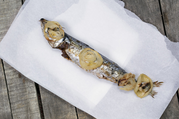 ein gebackener Makrelenfisch auf weißem Papier und Holzhintergrund - Foto, Bild