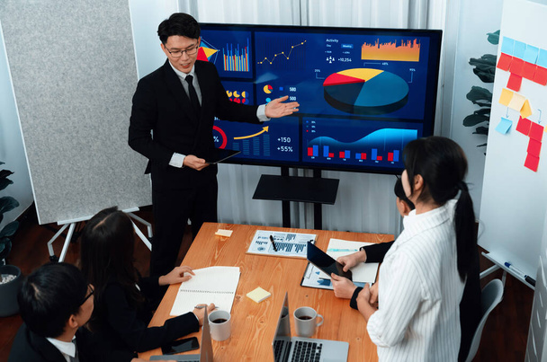 Confidence and asian businessman give presentation on financial analyzed by business intelligence in dashboard report to other people in board room meeting to promote harmony in workplace. - 写真・画像