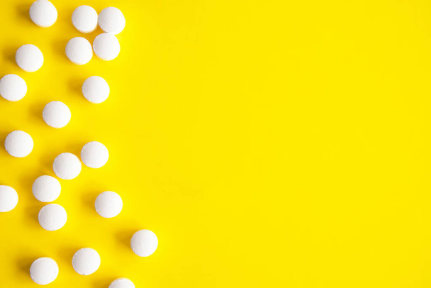 Ramka wykonana z tabletek. Żółte tło z białymi okrągłymi tabletkami, dodatki z boku. Projekt tekstu. Bezpośrednio powyżej widoku - Zdjęcie, obraz