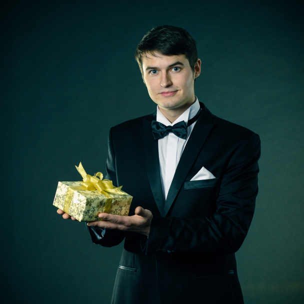 Man in a tuxedo gives a gift - Foto, Imagen