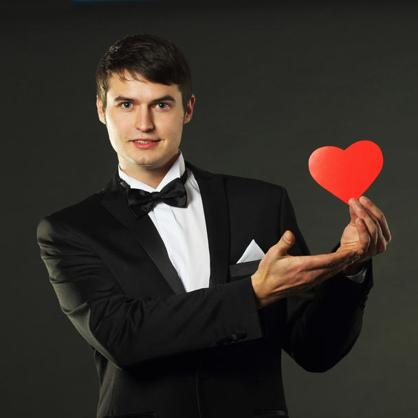 Man in a tuxedo with a red paper heart - Fotoğraf, Görsel