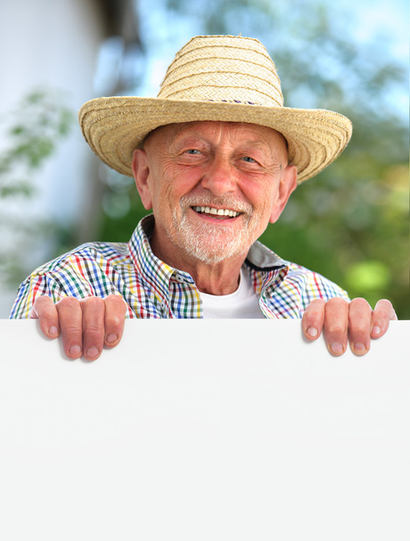 senior man with a straw hat holds a blank board - Fotografie, Obrázek
