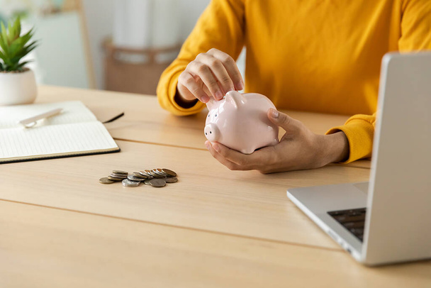 Saving money investment for future. Female woman hands holding pink piggy bank and putting money coin. Saving investment budget business wealth retirement financial money banking concept - Фото, зображення