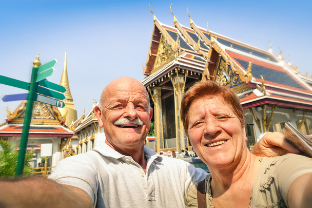 Ανώτερος ευτυχισμένο ζευγάρι λαμβάνοντας μια selfie στο Grand Palace ναούς στην Μπανγκόκ - Ταϊλάνδη ταξίδια περιπέτειας σε προορισμούς της Ασίας - έννοια του ενεργού ηλικιωμένους και διασκέδαση σε όλο τον κόσμο με τις νέες τεχνολογίες - Φωτογραφία, εικόνα