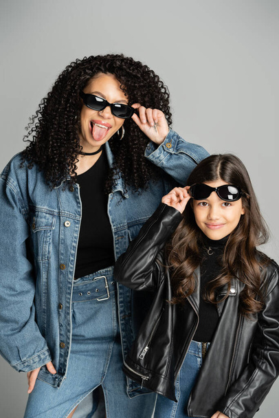 Fashionable parent and daughter posing with sunglasses isolated on grey  - Фото, изображение