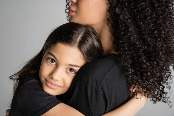 Портрет дев'ятнадцяти дітей обіймає кучеряву маму і дивиться на камеру ізольовано на сірому
  - Фото, зображення