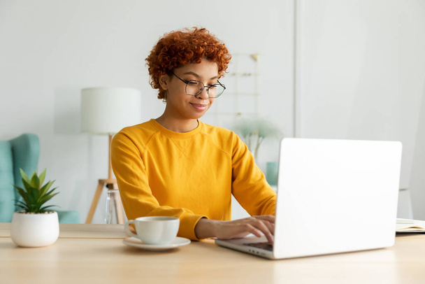 African american girl using laptop at home office looking at screen typing chatting reading writing email. Young woman having virtual meeting online chat video call conference. Work learning from home - Foto, imagen