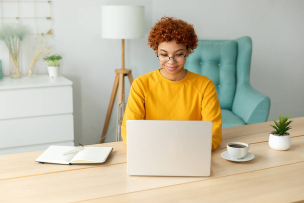 African american girl using laptop at home office looking at screen typing chatting reading writing email. Young woman having virtual meeting online chat video call conference. Work learning from home - Fotoğraf, Görsel