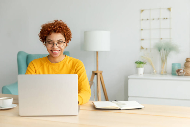 African american girl using laptop at home office looking at screen typing chatting reading writing email. Young woman having virtual meeting online chat video call conference. Work learning from home - Foto, imagen
