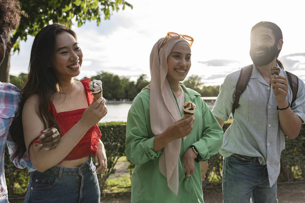 ποικίλες φίλες που τρώνε παγωτό στο πάρκο - εστιάστε στην αραβική γυναίκα - - Φωτογραφία, εικόνα