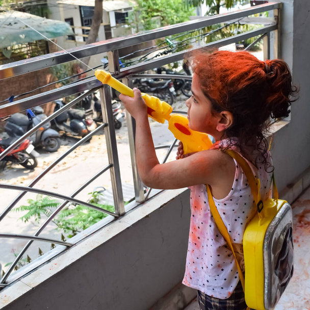 Dolce bambina indiana che gioca a colori al festival di Holi, con pichakaree piene di colori, celebrazioni del festival di Holi a Delhi, India - Foto, immagini