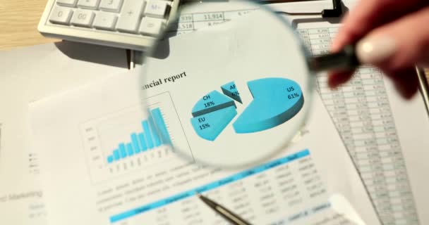 Manager hand holding magnifying glass over graph in financial report closeup 4k movie slow motion. Strategies in business development and work analysis concept - Footage, Video