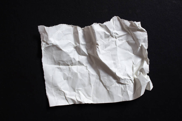 Crumpled torn paper piece isolated on a black background. Ripped paper sheet. - Fotoğraf, Görsel