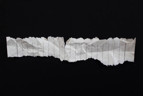 Crumpled torn paper piece isolated on a black background. Ripped paper sheet. - Fotoğraf, Görsel