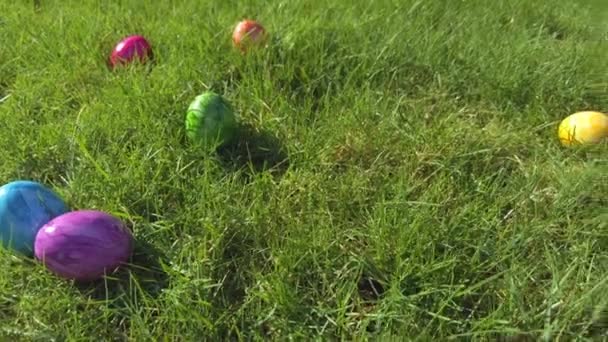 Œufs de Pâques cachés dans l'herbe verte prête pour la chasse aux œufs de Pâques jeu enfants mains ramassant des œufs dans la pelouse. jeu de printemps traditionnel activité de plein air pour les enfants. Joyeux concept de Pâques coloré peint - Séquence, vidéo