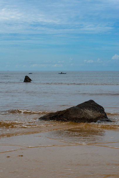 Na zdjęciu zapierający dech w piersiach widok na spokojną plażę z krystalicznie czystymi wodami i łagodnymi falami okrążającymi brzeg. Niekończący się odcinek złotego piasku jest usiany parasolami słonecznymi, krzesłami plażowymi i palmami. Głęboko błękitne morze rozciąga się t - Zdjęcie, obraz