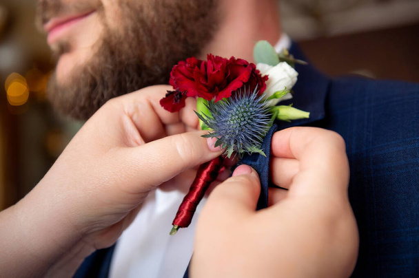 flowers bouquets bouquets and boutonnieres red flower in boutonniere and navy blue jacket mom pinning her son's boutonniere - Foto, imagen