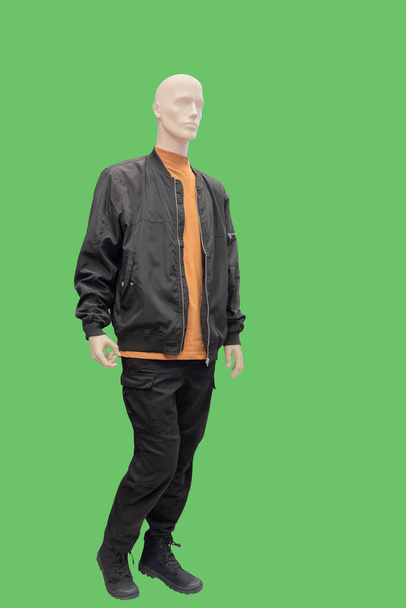 Full length image of a male display mannequin wearing black jacket and orange turtleneck isolated on green background - Photo, Image