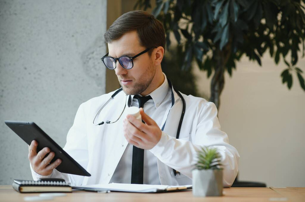 male doctor using tablet computer at his office. General practitioner using digital tablet at his clinic - Foto, Bild