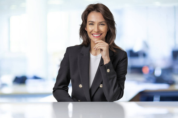an attractive businesswoman wearing black blazer while sitting  - Zdjęcie, obraz