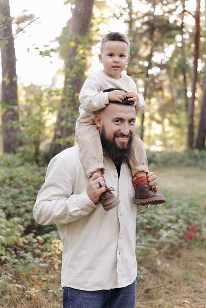 Father's day. Smiling dad holding his toddler son on shoulders look at camera outdoor at nature.Family spend and enjoy time together. Happy fatherhood and childhood, family love, togetherness concept. - Fotografie, Obrázek