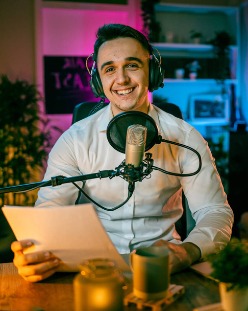 One man caucasian male blogger or vlogger gesticulating while streaming video podcast in broadcasting studio use microphone and headphones famous influencer shooting video for channel podcast - Fotografie, Obrázek