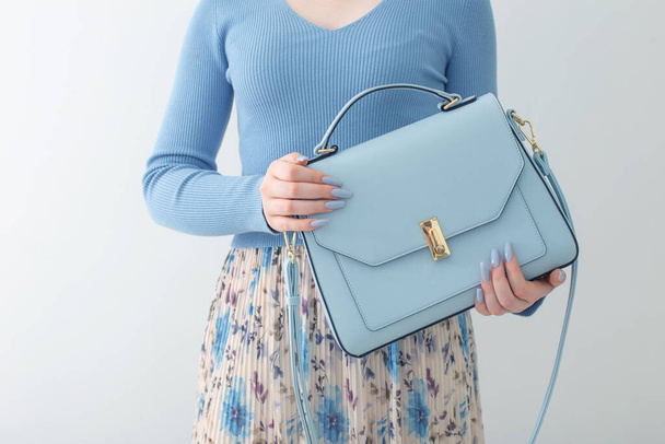 young girl in blue blouse  and pleated skirt with blue handbag on white background - Fotografie, Obrázek