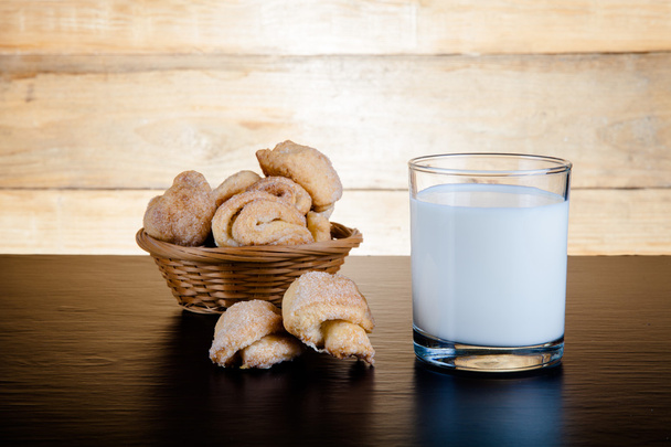 Basket of cookie and glass of milk on a black table against old  - Фото, изображение