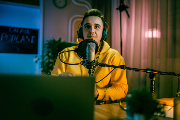 focus on microphone One man caucasian male blogger or vlogger gesticulating while streaming video podcast in broadcasting studio famous influencer shooting video for channel podcast - Valokuva, kuva