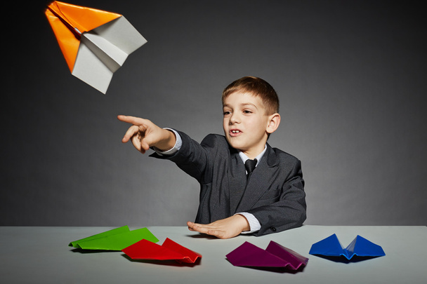Boy in business suit launching color paper plane - Фото, изображение