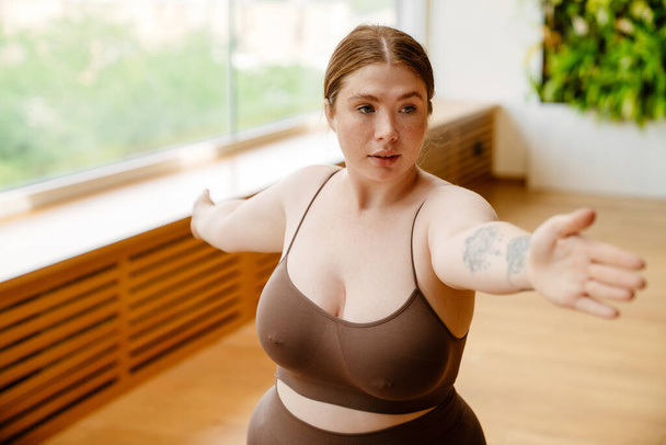 Ginger young woman doing exercise during yoga practice indoors - Foto, Imagem
