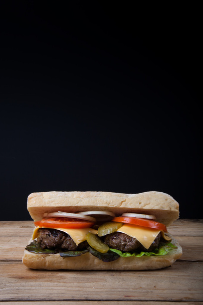 Kotitekoinen voileipä puupöydällä mustalla taustalla
 - Valokuva, kuva