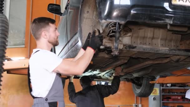 Een professionele automonteur onderzoekt een auto bij een autodienst en voert een reeks tests en inspecties uit. Auto-onderhoud en diagnostiek - Video