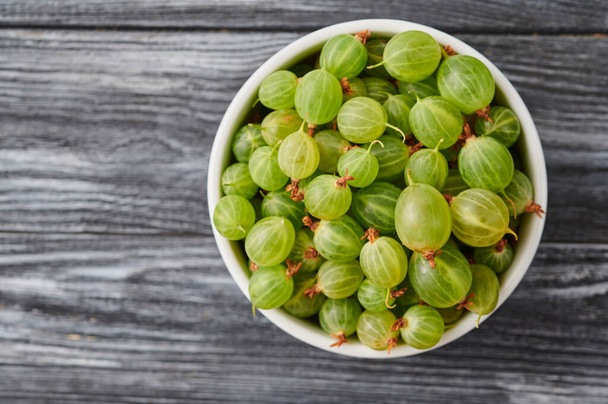 ripe agrus, gooseberries in a plate on the table, close-up top view - Foto, Bild
